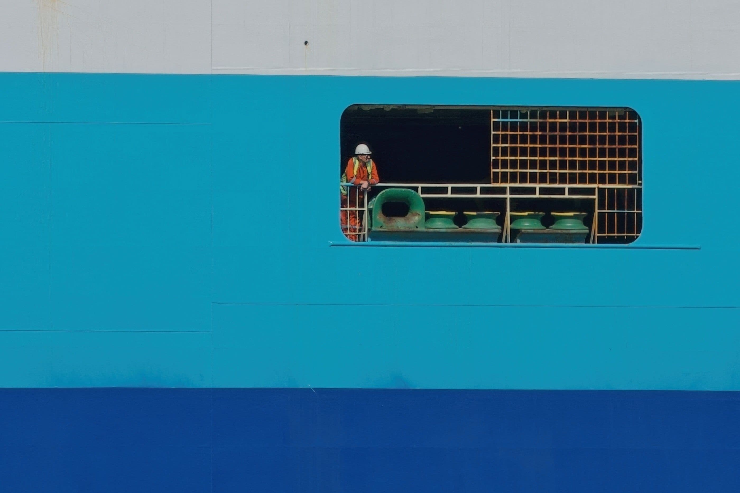 A maritime worker looking out the side of a ship